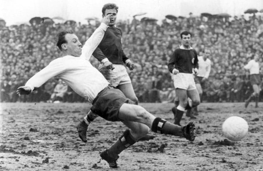 Uwe Seeler, noch als aktiver Spieler, bei einer Grätsche um den Ball.