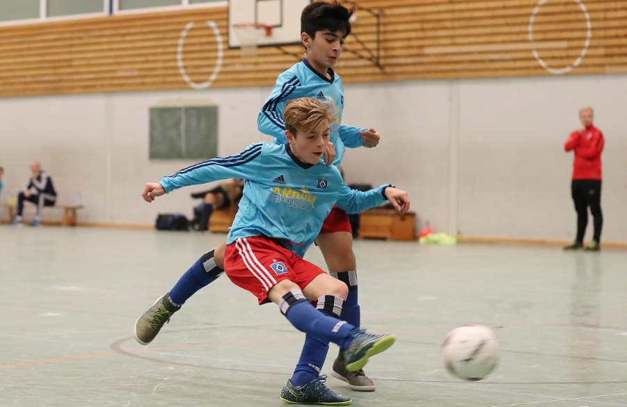 U13-Kicker Lenny Glissmann schießt aufs Tor, Milad Nejad begutachtet den Schuss aus dem Hintergrund.