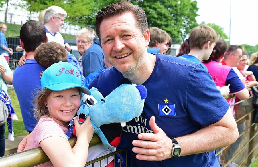 Christian Titz posiert mit einem jungen Fan am Trainingsplatz.