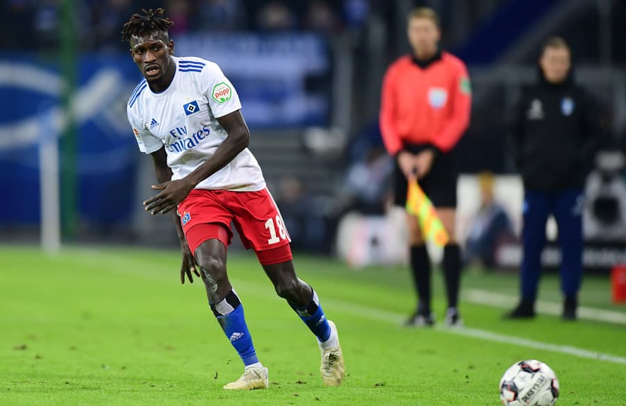 Bakery Jatta treibt im Spiel gegen Union Berlin den Ball nach vorn. Im Hintergrund an der Seitenlinie steht Hannes Wolf.