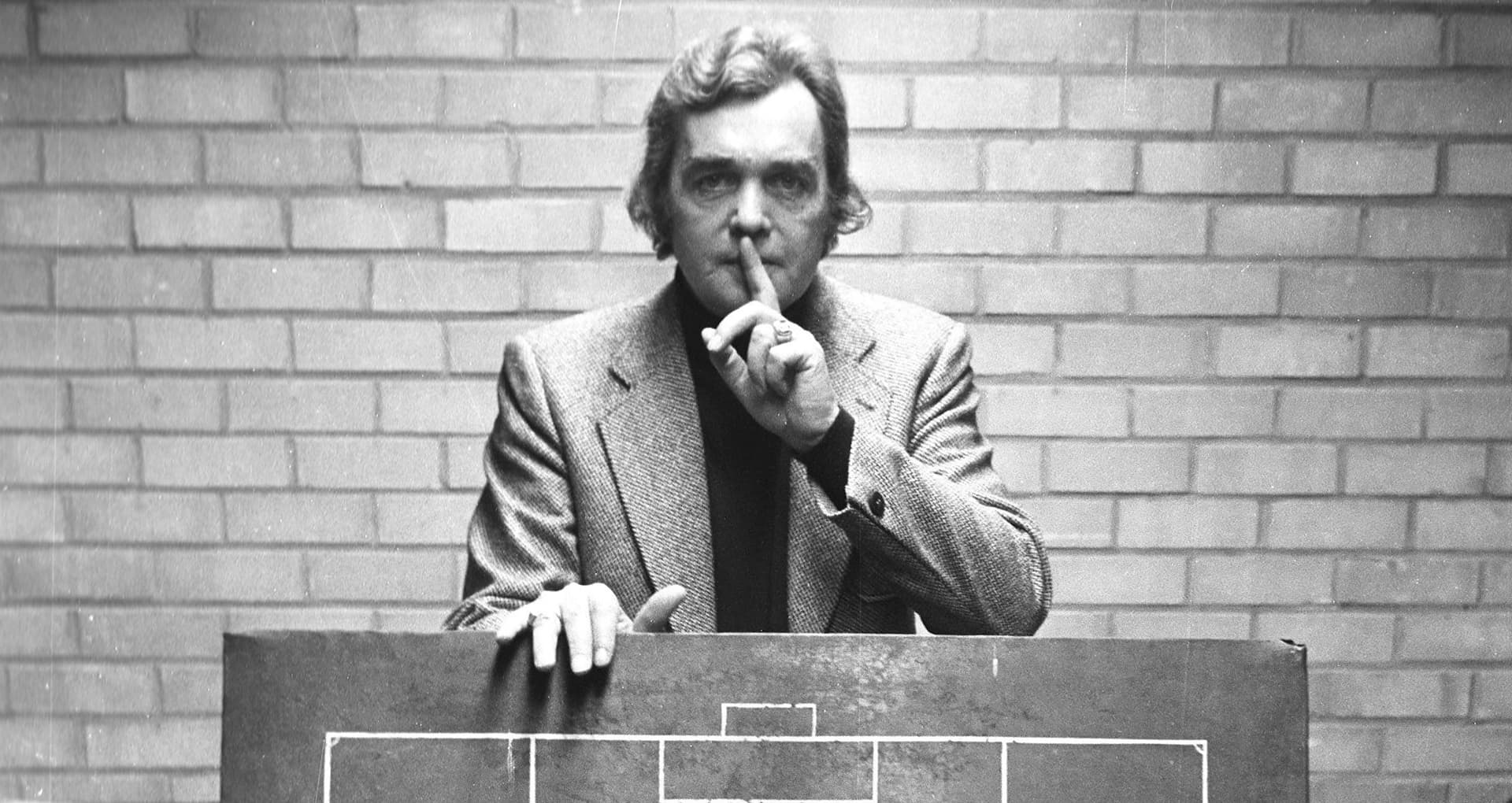 Ernst Happel mit Taktiktafel und Zeigefinger vor den Lippen