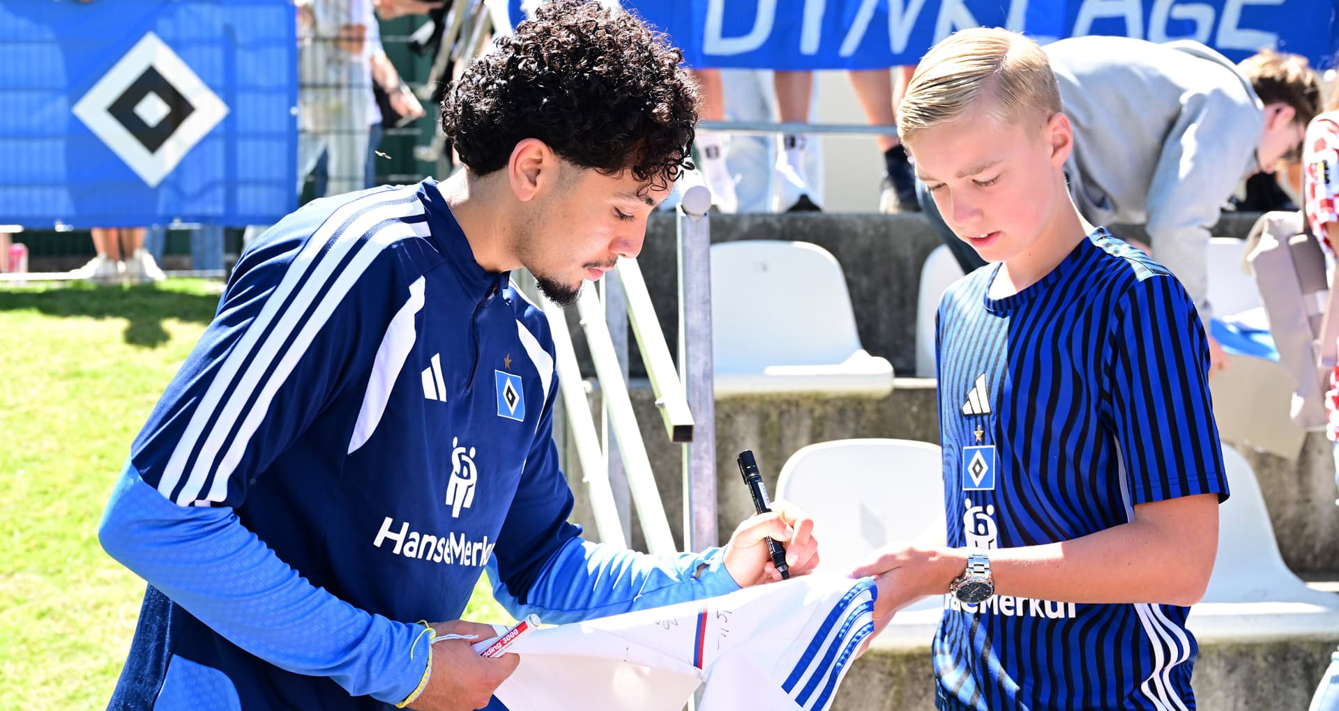 Bilal Nadir gibt einem Fan im Trainingslager ein Autogramm auf sein Trikot