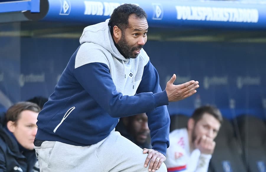 Daniel Thioune steht am Spielfeldrand und zeigt mit der Hand. 