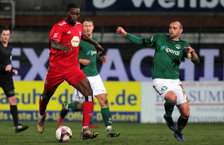 Patric Pfeiffer führt den Ball am Fuß, ein Lübecker setzt zum Zweikampf an.