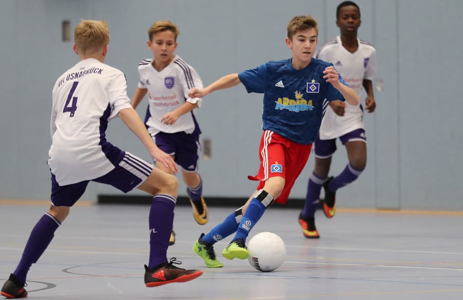 Der U15-Kicker des HSV setzt sich in der Halle gegen seine Gegenspieler durch