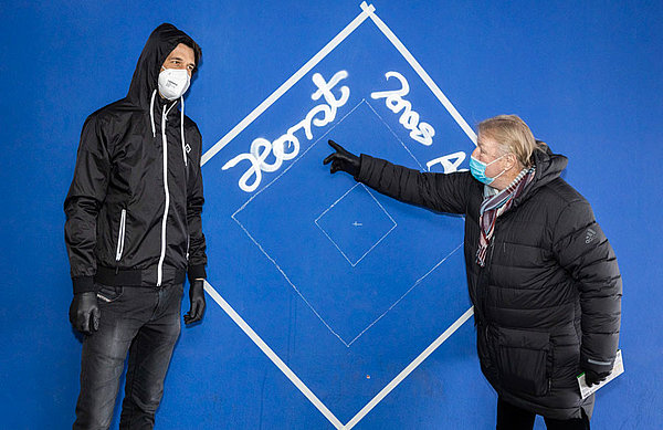 Neben weiteren HSV-Mitarbeitenden halfen auch HSV-Vorstand Jonas Boldt (links) und Direktor Nachwuchs Horst Hrubesch (rechts) bei der Erstellung des neuen Graffitis im Bereich der Nordtribüne im Volksparkstadion.