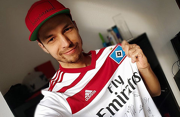 FIFA-Profi Daniel Tissarek hat ein HSV-Trikot an und hält die Raute in die Kamera.