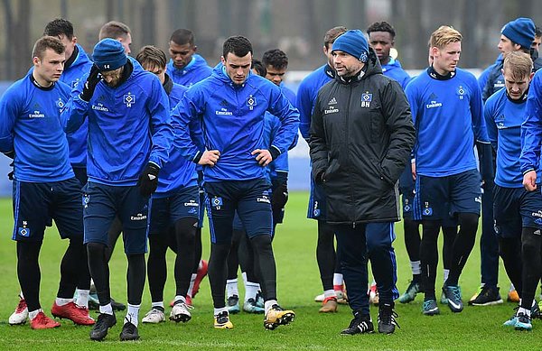 Bernd Hollerbach geht in einer Gruppe mit den Spielern über den Trainingsplatz.