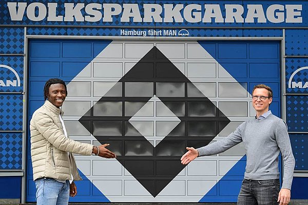 Michael Mutzel (re.) freut sich darauf, Aaron Opoku in der kommenden Saison wieder beim HSV begrüßen zu dürfen. "Er hat einen riesen Schritt gemacht", so der Sportdirektor. Aaron Opoku und Michael Mutzel stehen sich v or dem Volksparkstadion in drei Meter Abstand gegenüber und geben sich die Hand.