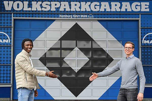 Aaron Opoku und Michael Mutzel stehen sich v or dem Volksparkstadion in drei Meter Abstand gegenüber und geben sich die Hand.