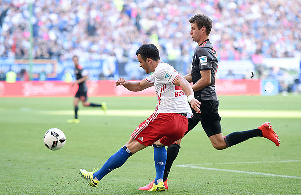 Filip Kostic schlägt bedrängt von Thomas Müller eine Flanke.