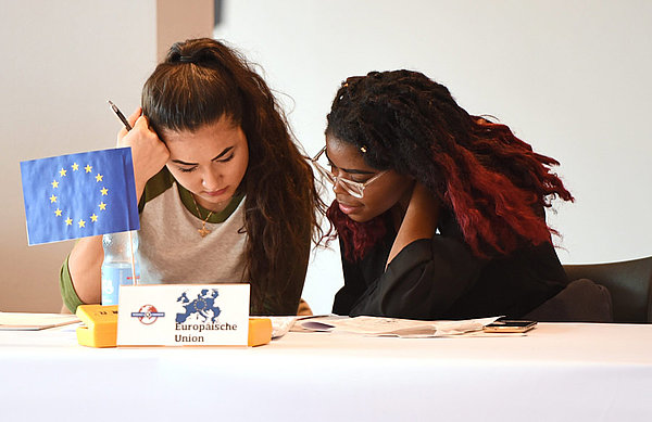 Zwei Schüler sitzen konzentriert am Verhandlungstisch.