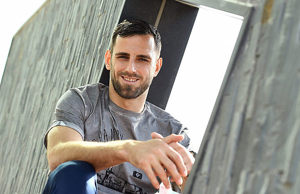 "Genug Werkzeuge, um erfolgreich Fußball zu spielen" - Mavraj geht selbstbewusst in die Aufgabe mit dem HSV. Mavraj sitzt auf einer Mauer.