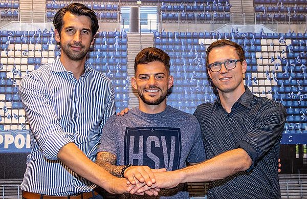 Sportvorstand Jonas Boldt, Tim Leibold und Sportdirektor Michael Mutzel stehen Hand in Hand zusammen. 