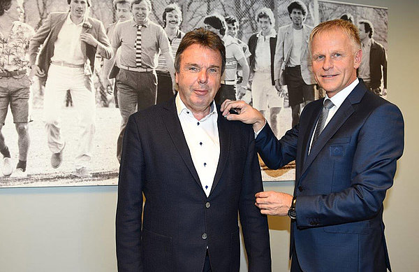 Jens Meier steckt Heribert Bruchhagen die silberne Ehrennadel ans Jacket.