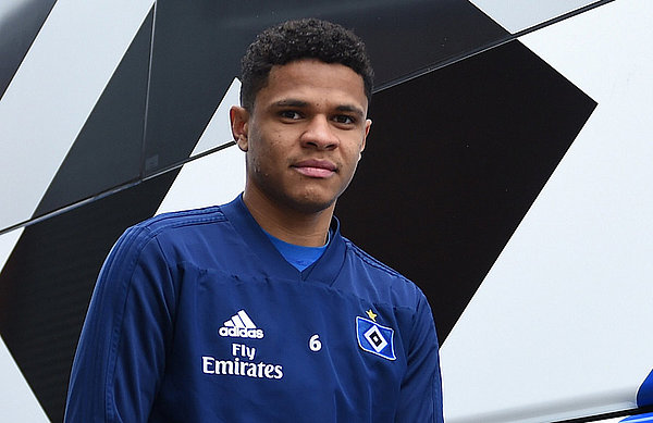 Douglas Santos steht in HSV-Trainingsklamotten vor dem HSV-Bus.