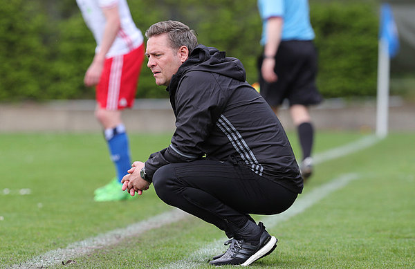 U21-Trainer Dirk Kunert in der Hocke am Seitenrand.