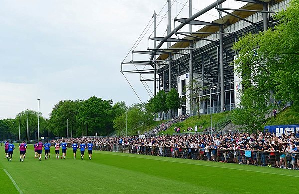 Rund 2.000 Fans stehen am Trainingsplatz. Im Hintergrund ist das Volksparkstadion zu sehen.