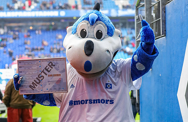 Der Dino steht im Volksparkstadion und präsentiert die 100-Euro-Schmuckurkunde.