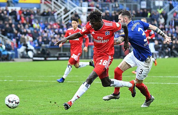Jatta setzt sich mit Ball im Laufduell gegen Schmidt durch.