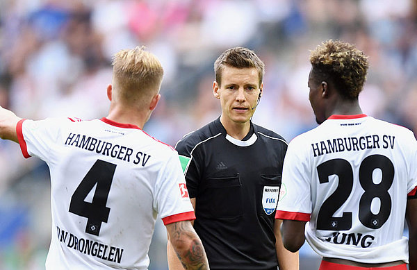 Rick van Drongelen und Gideon Jung stehen vor Schiedsrichter Daniel Siebert.