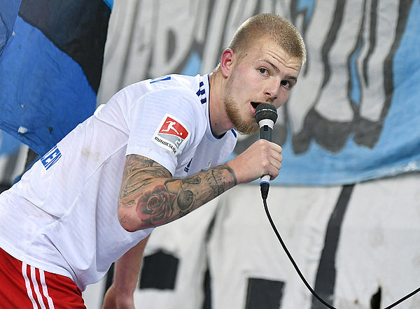 Rick van Drongelen mit einem Mikro vor der Nordtribüne.