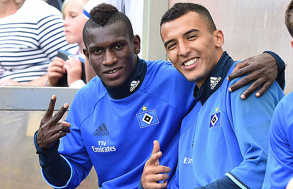 Nabil Bahoui fühlt sich sichtlich wohl innerhalb der Mannschaft. Mit Bakery Jatta scherzt er auf englisch. Deutsch will er unbedingt lernen. Nabil Bahoui und Bakery Jatta sitzen auf der Auswechselbank und strecken den Daumen nach oben.