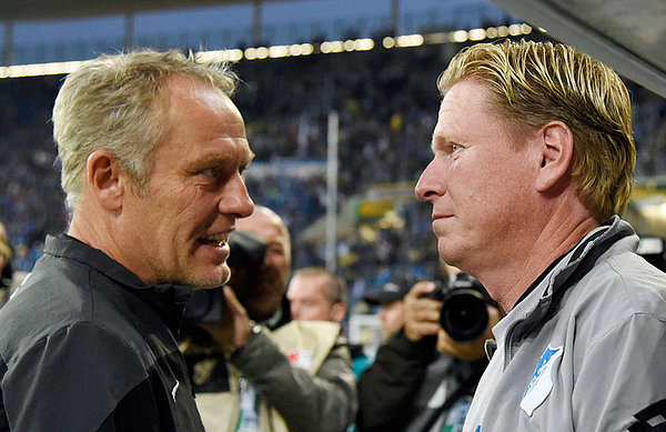 Markus Gisdol und Christian Streich stehen sich vor der Trainerbank gegenüber.