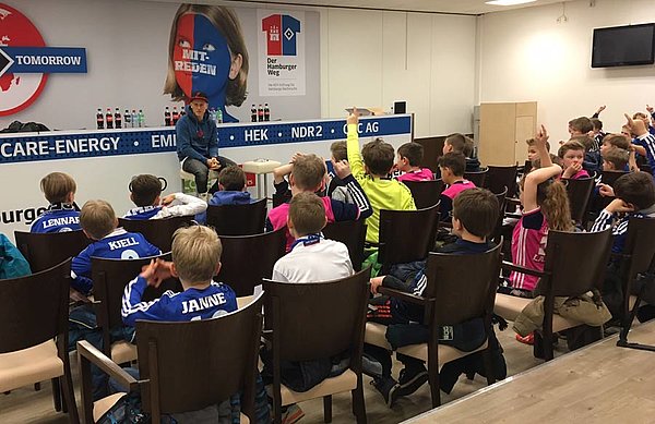 Matthias Ostrzolek sitzt im Pressekonferenzraum vor den Fußballschulen-Teilnehmern.