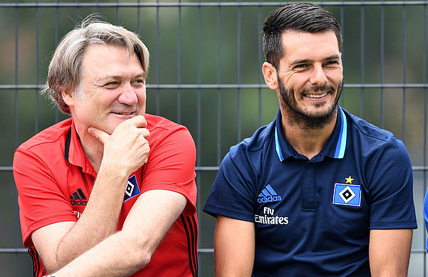Emir Spahic sitzt neben Dietmar Beiersdorfer auf der Bank am Trainingsplatz.