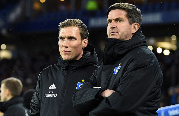 Hannes Wolf und Ralf Becker blicken vor einem Punktspiel im Volksparkstadion gemeinsam aufs Feld.