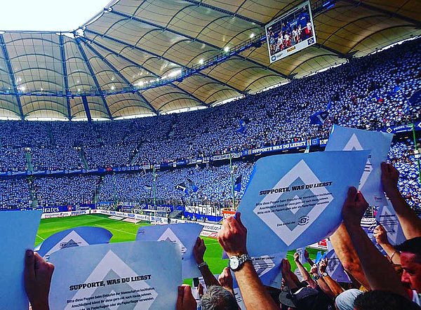 Die Fans im Volksparkstadion halten Pappen mit der Raute hoch.