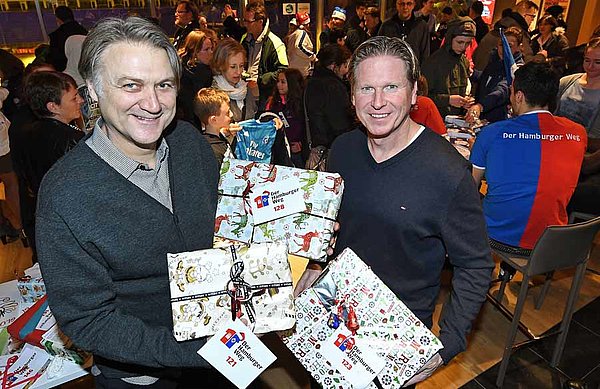 Dietmar Beiersdorfer und Markus Gisdol stehen mit Geschenken in der Hand im VIP-Raum des Volksparkstadions.