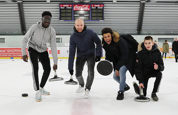 Tim Reddersen und drei Spieler stellen szenisch eine Wurf mit dem Eisstock nach.