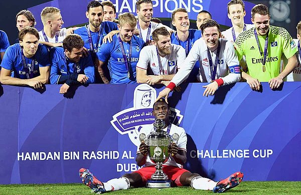 Bakery Jatta sitzt bei der Siegerehrung mit dem Pokal vor der Mannschaft.