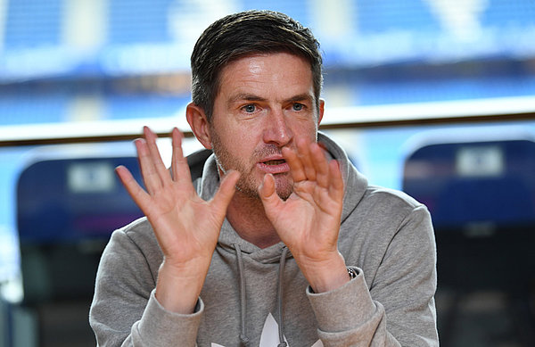 Ralf Becker betont, wie wichtig in den kommenden Wochen die Einsatzbereitschaft jedes Einzelnen und der Zusammenhalt zwischen allen HSVern sein wird. Ralf Becker gestikuliert.
