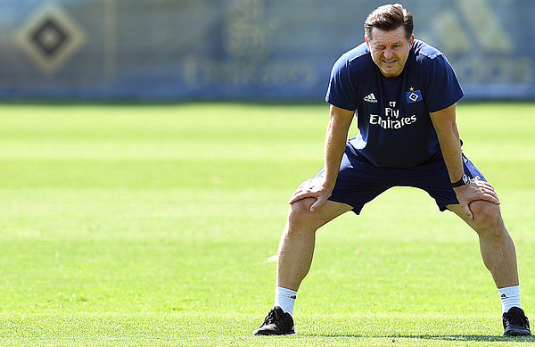 Christian Titz steht mit Händen auf den Oberschenkeln auf dem Trainingsplatz.