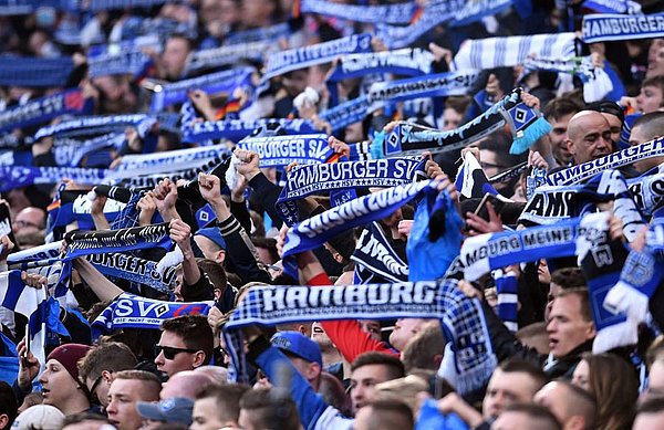 Das Warten hat ein Ende: Die Bundesliga beginnt wieder. Der HSV setzt auf die lautstarke Unterstützung seiner Fans. HSV-Fans halten ihre Schals hoch.