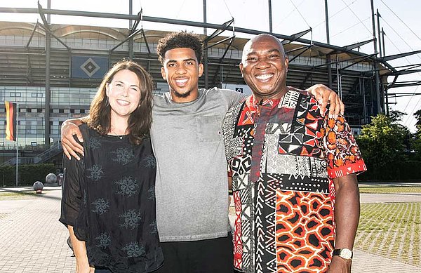 Xavier Amaechi steht mit seiner Mutter und seinem Vater vor dem Volksparkstadion.