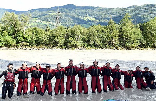 Die Spieler stehen am Flusslauf Arm in Arm.